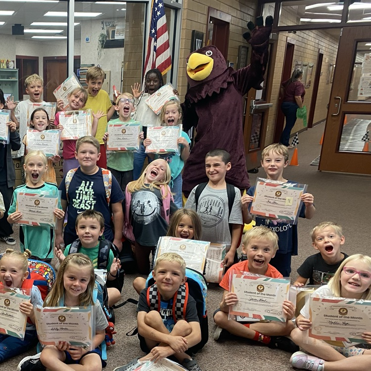many students holding certificates and standing next to a Hawk mascot