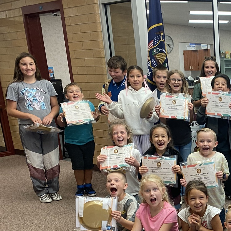 many students holding certificates in front of the school office