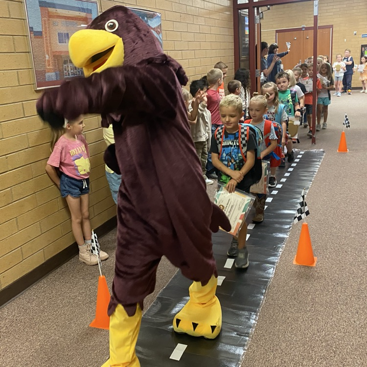 students following a Hawk mascot and marching down the hall