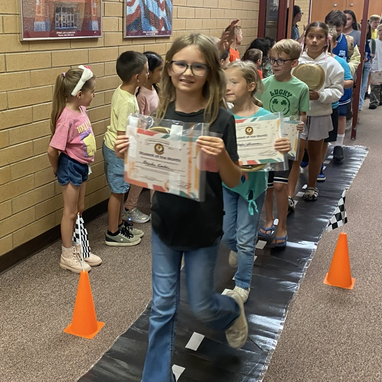 students marching down the hall while holding their certificates