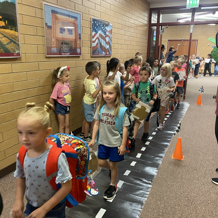 kindergarten students marching down the hall while being cheered on by other students