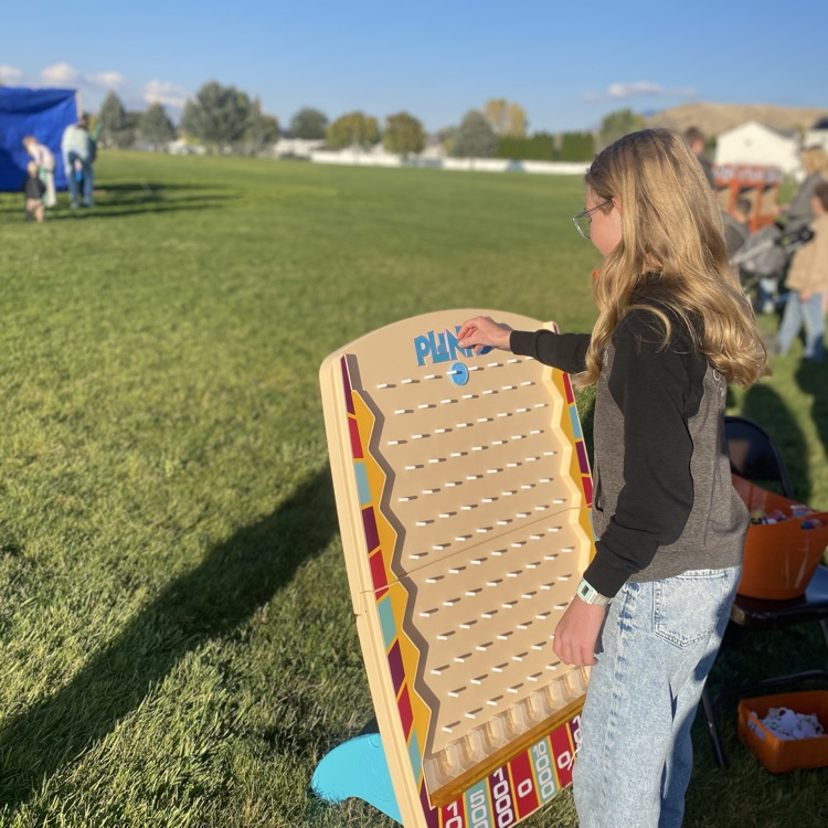 a student dropping a playing piece into Plinko