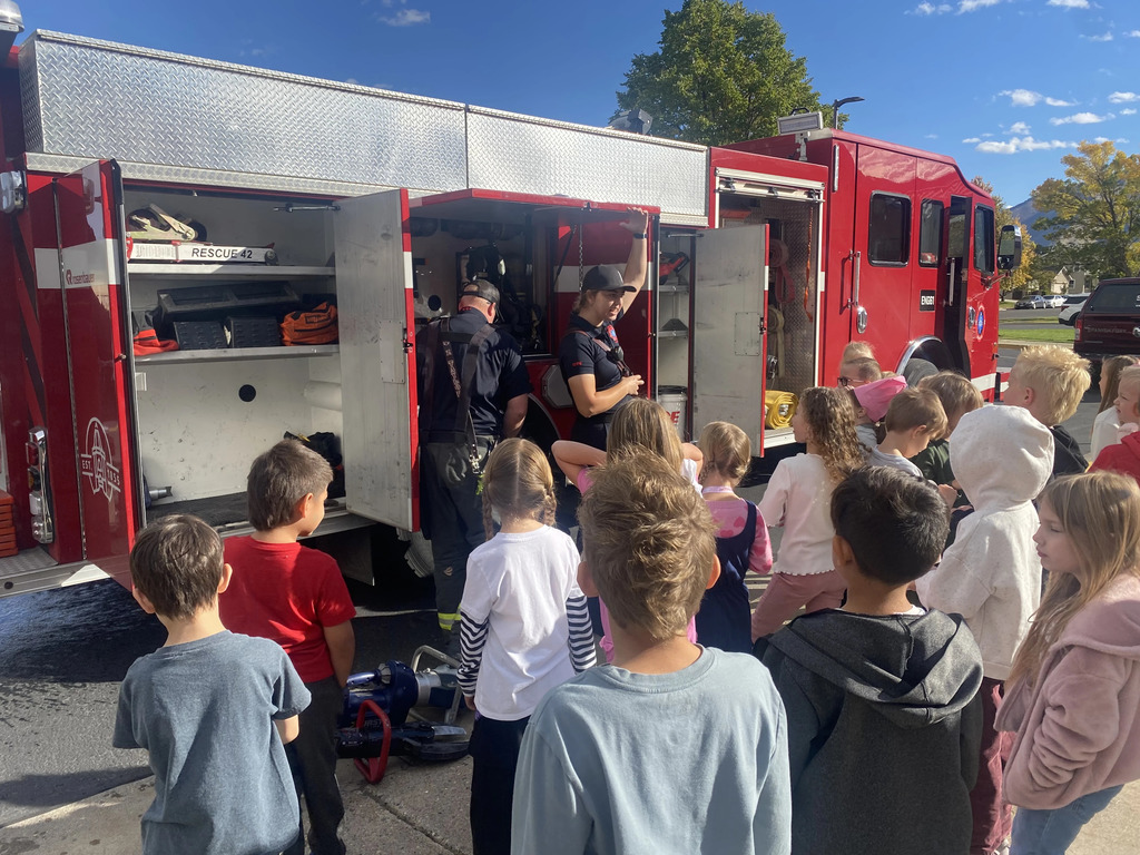 students looking at all the tools of a firetruck