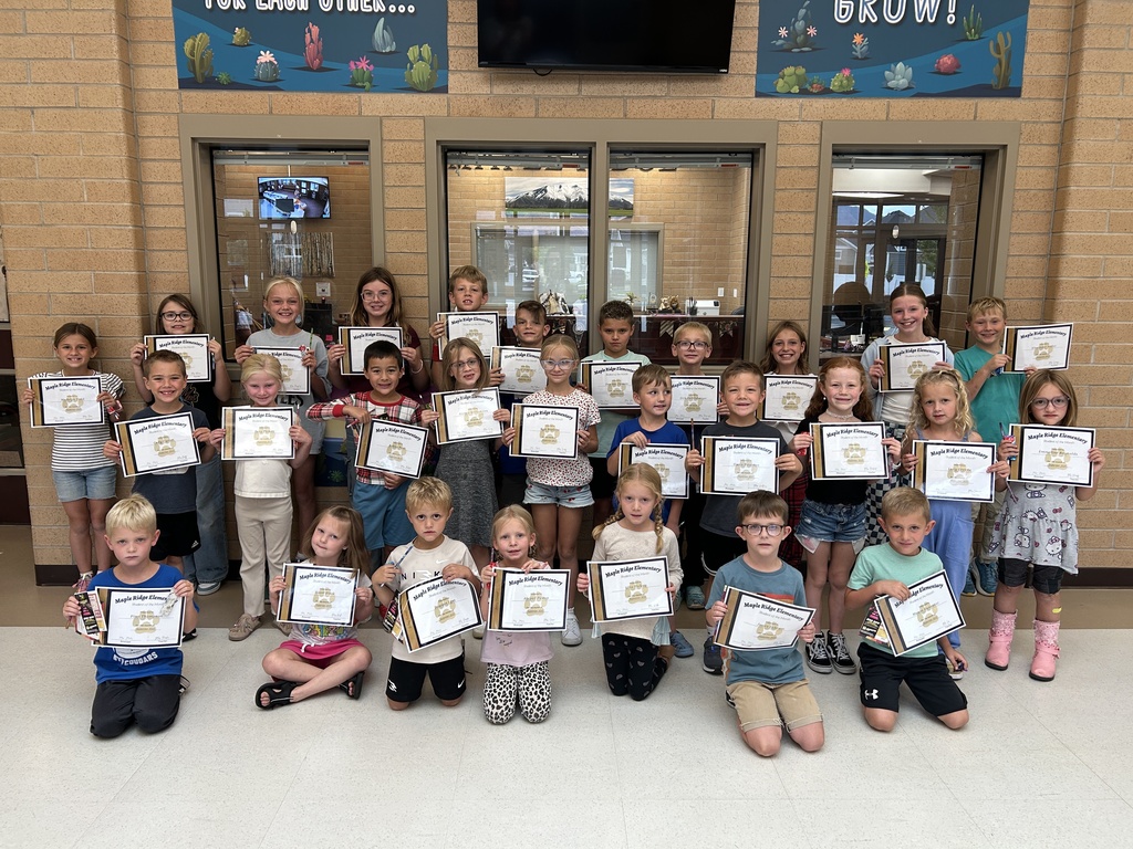 Students in front foyer holding their Student of the Month certificates.