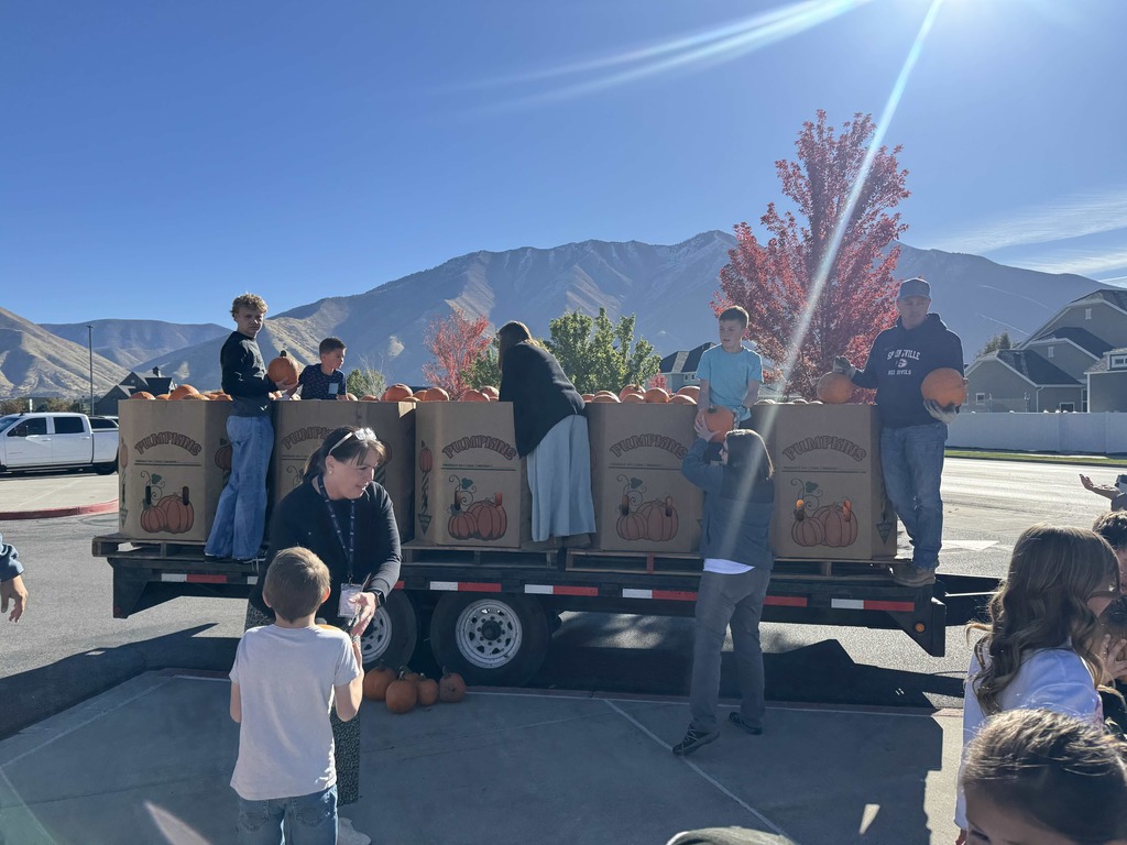 Adults handing pumpkins to students.