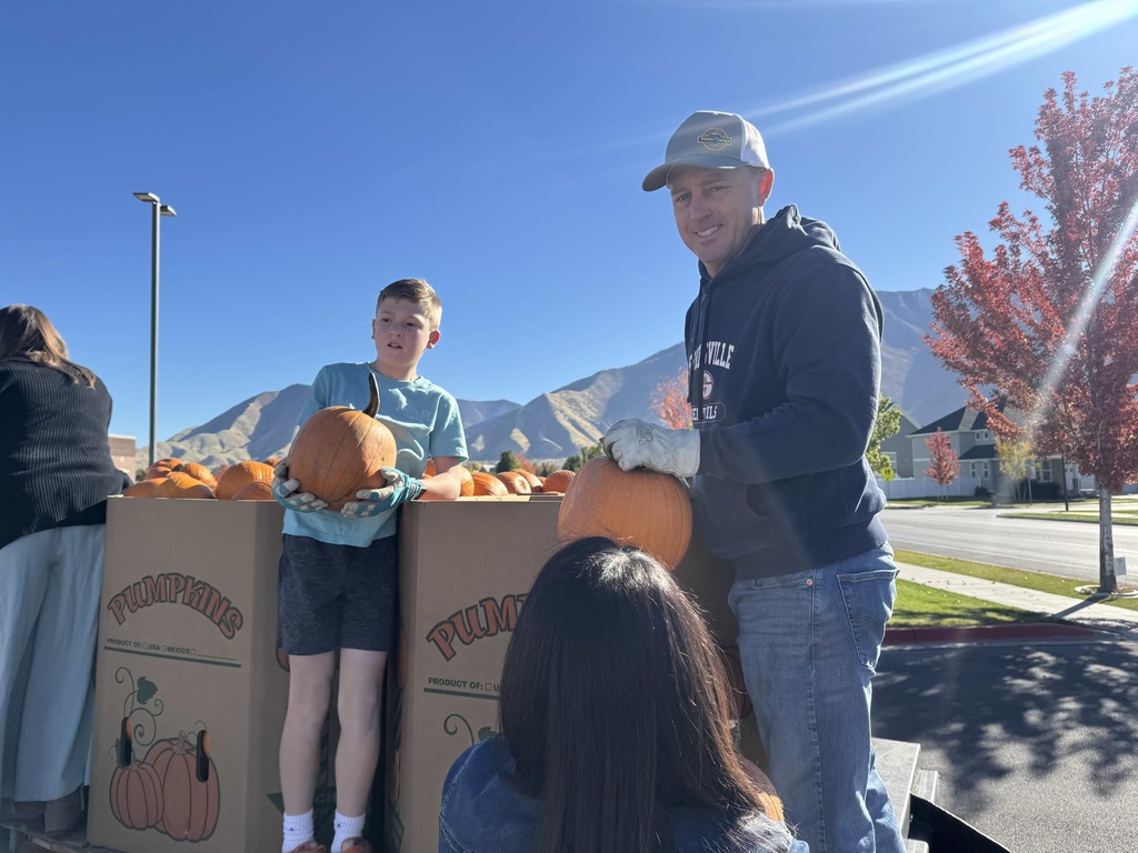 Adult and child handing out pumpkins.