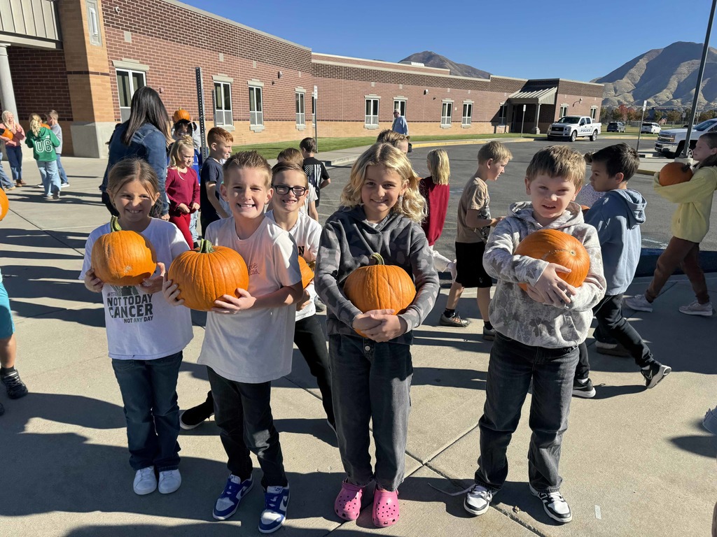 Students holding pumpkins.