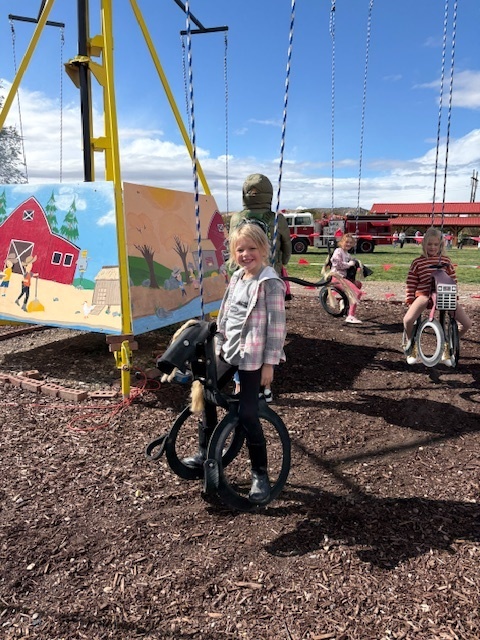students riding on swings that look like horses made out of tires
