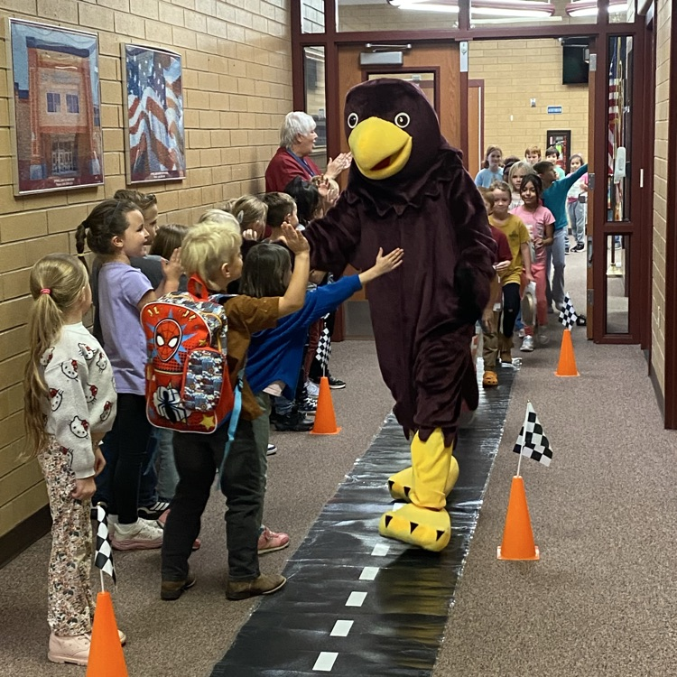 a Hawk mascot giving a high five to a student in the hallway 