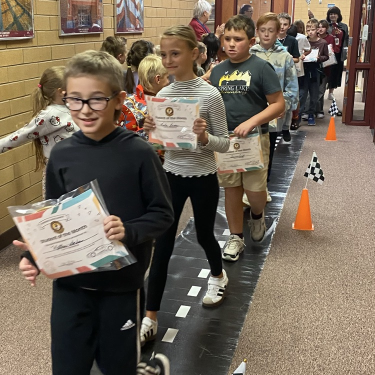 students walking down a hall while cheered for by students