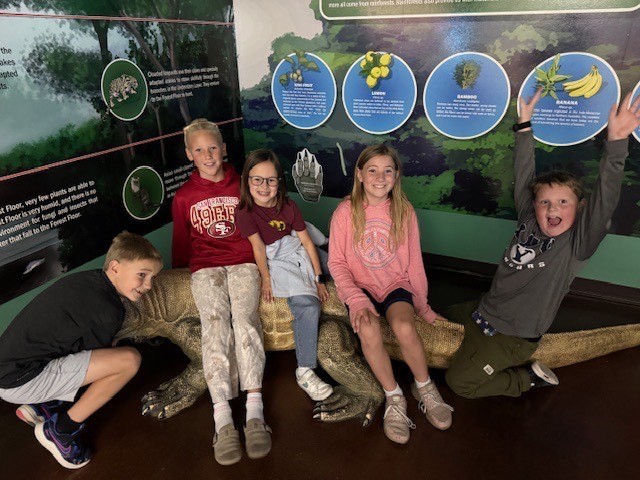 Students sitting on a replica of an alligator.