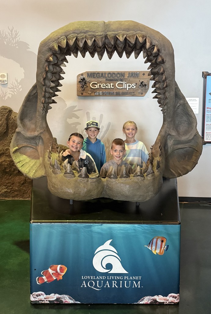 Students standing in a large fish jaw.