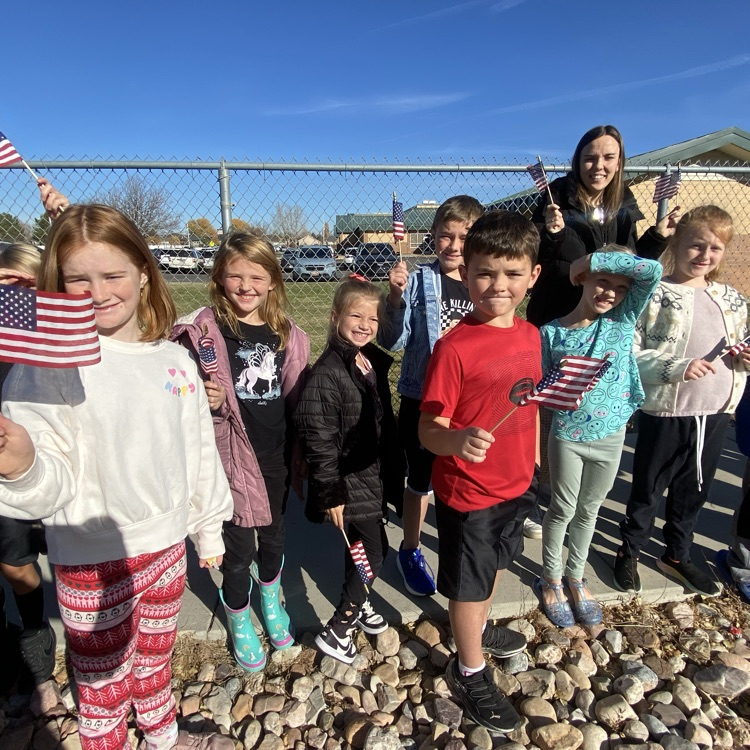 a group of second graders with their teacher waving flags