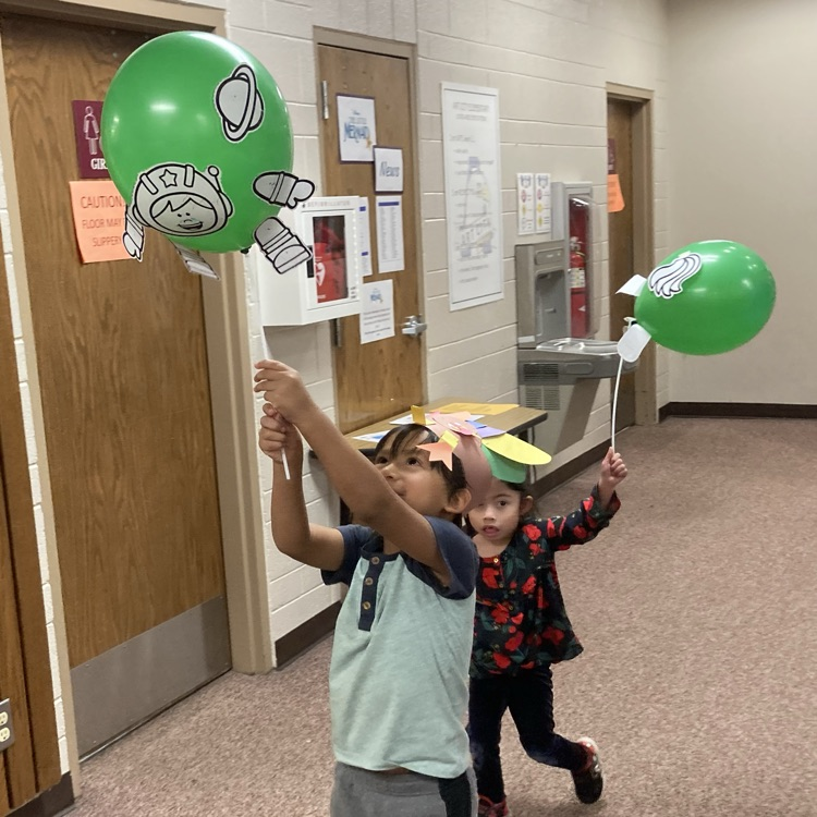 Students holding up their ballon creations walking the halls