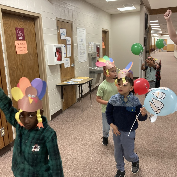 students holding up their ballon creations walking the halls