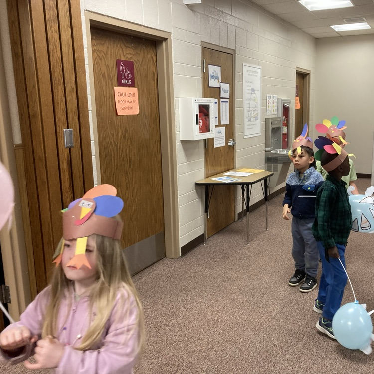 students holding up their ballon creations walking the halls