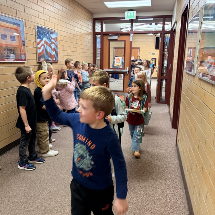 a student waving while walking down the hall