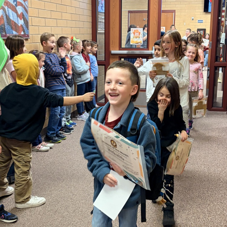 kids happily walk down the hall while kids cheer for them
