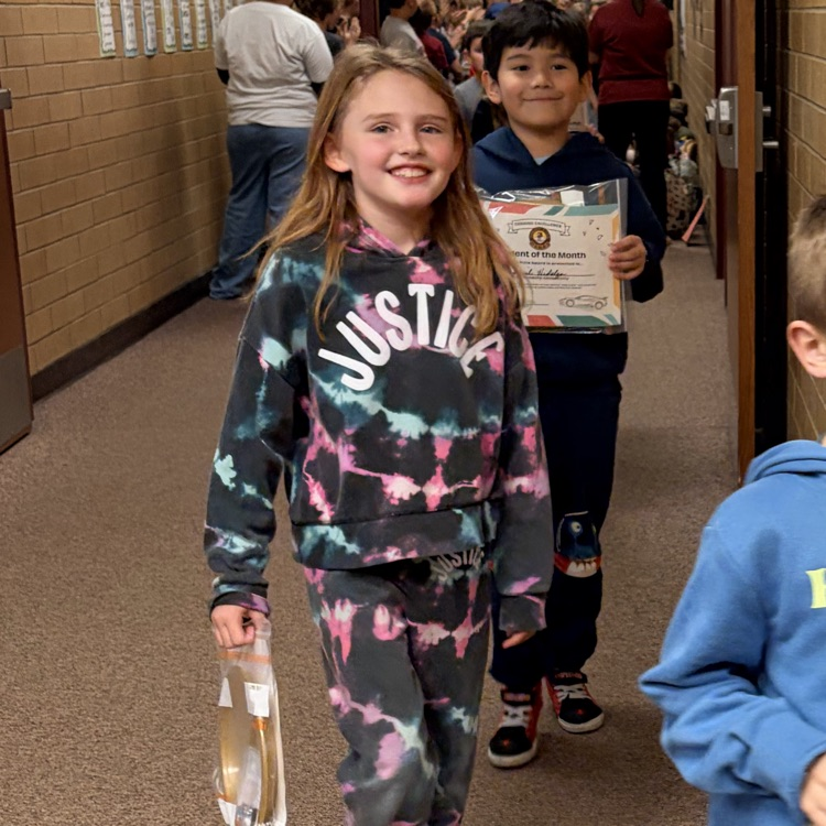 two kids smiling while walking down the hall