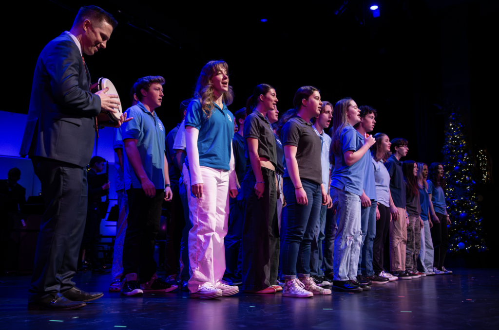 Fine arts Assembly- Chamber Choir on stage with Christmas trees