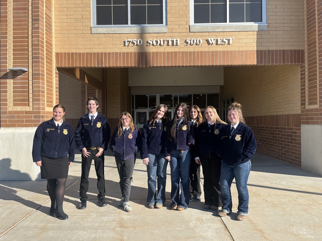 8 high school students standing in front of the school in matching FFA jackets