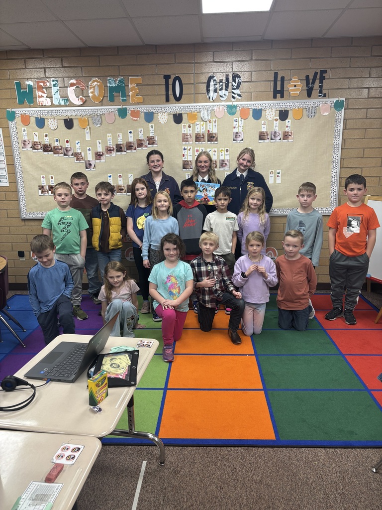 a second grade class in two rows in front of 3 FFA students. The first row is kneeling. The second row is standing.