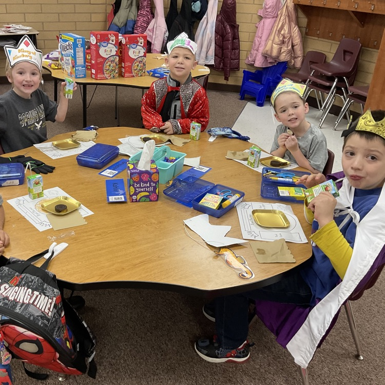 four boys sitting at a table eating Oreos