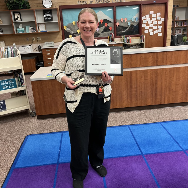 Celeste Penick smiling while holding a crystal apple and a certificate 