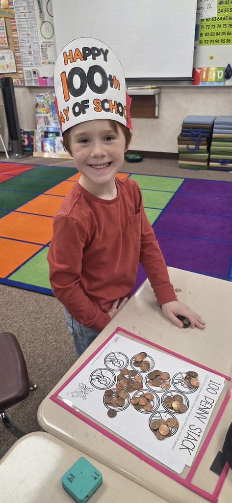 A smiling young boy wearing an orange and black crown that says "Happy 100th Day of School"