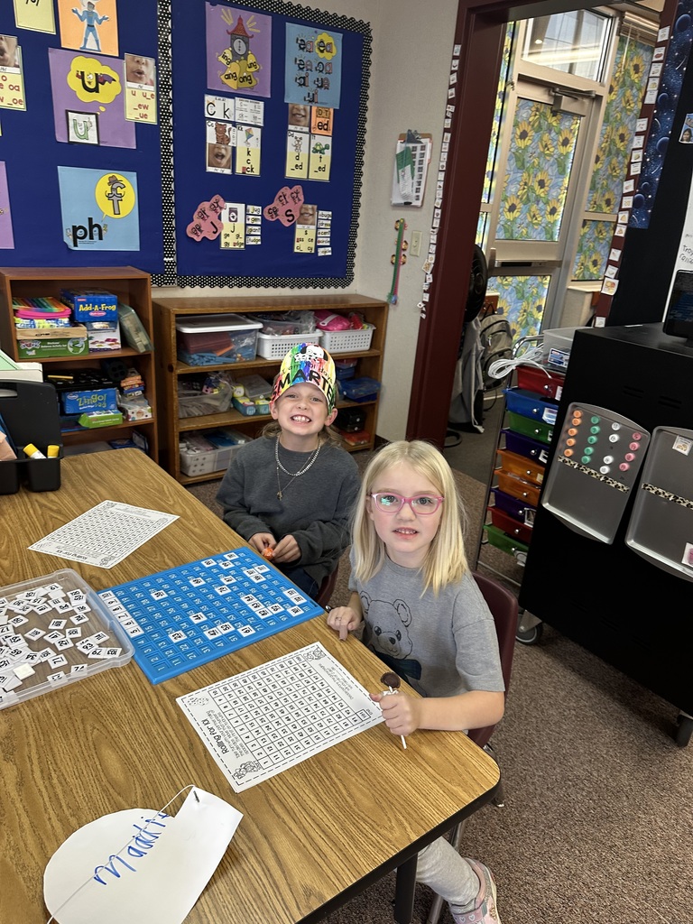 two young girls smiling for the camera while doing an activity on a 100s board