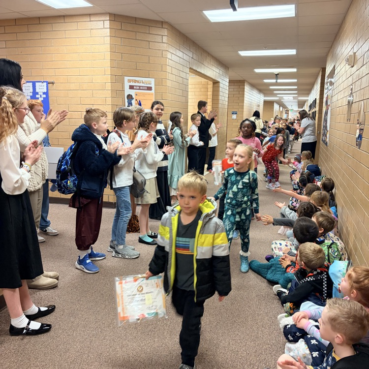 a line of kids walking down the hall while other kids cheer for them