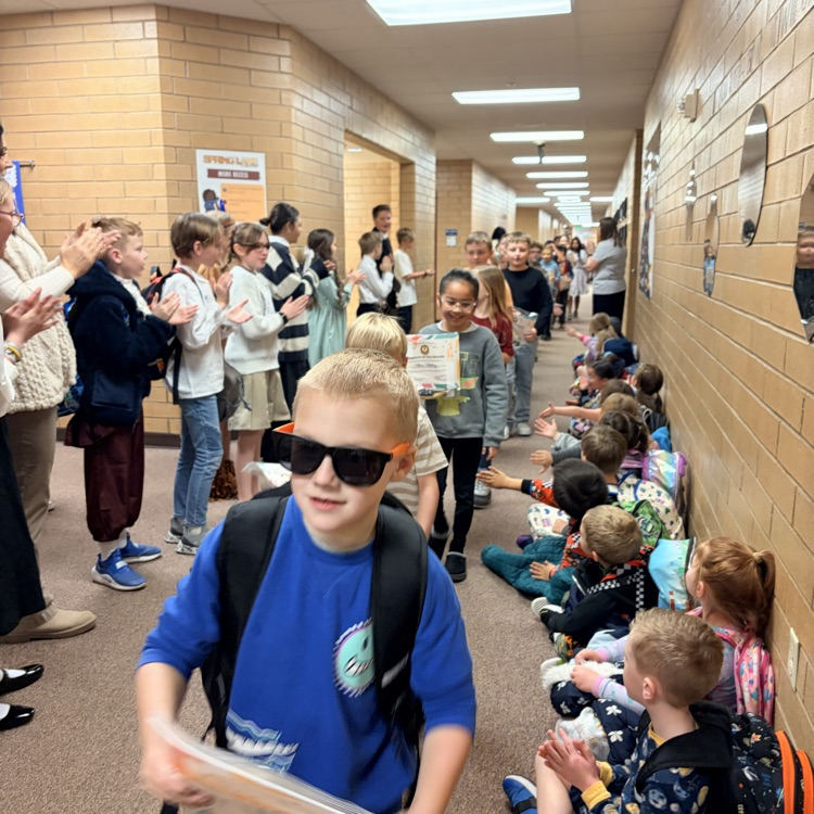 a line of kids walking down the hall while other kids cheer for them