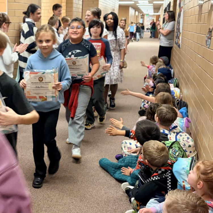 a line of kids walking down the hall while other kids cheer for them