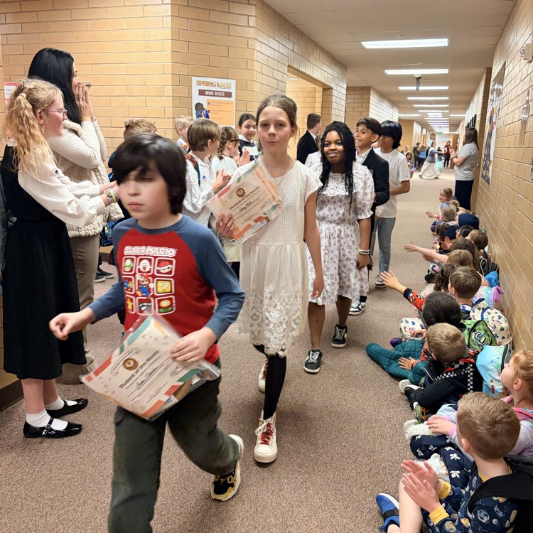 a line of kids walking down the hall while other kids cheer for them