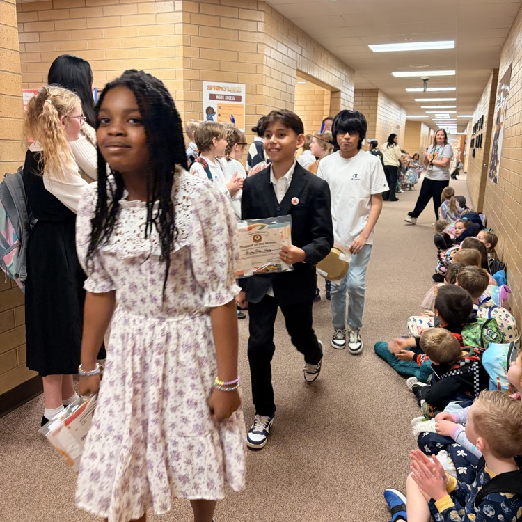 a line of kids walking down the hall while other kids cheer for them