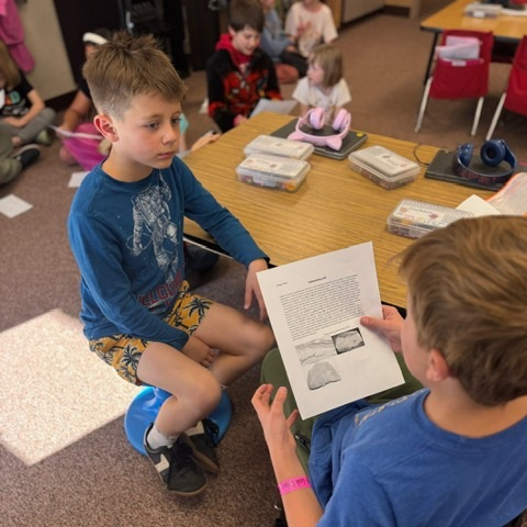 A 4th grade student reading to a 1st grade student 
