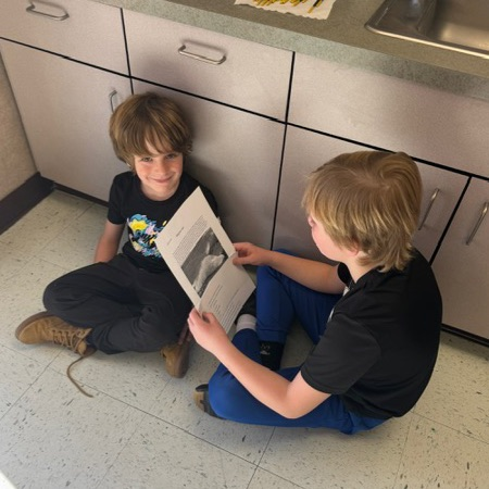 A 4th grade student reading to a 1st grade student 