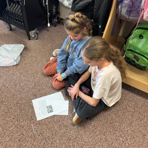 A 4th grade student reading to a 1st grade student 