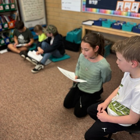 Multiple 4th grade students reading to 1st grade students 