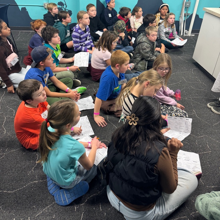 students sitting on the floor learning a lesson