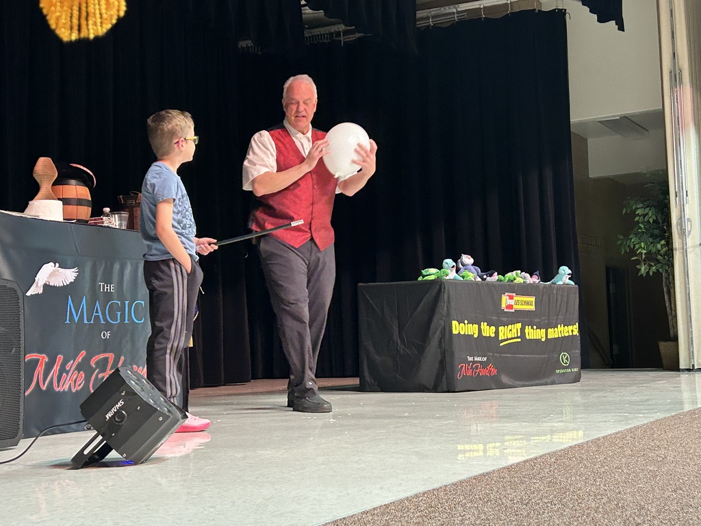 Magician with a student doing a trick with a balloon.
