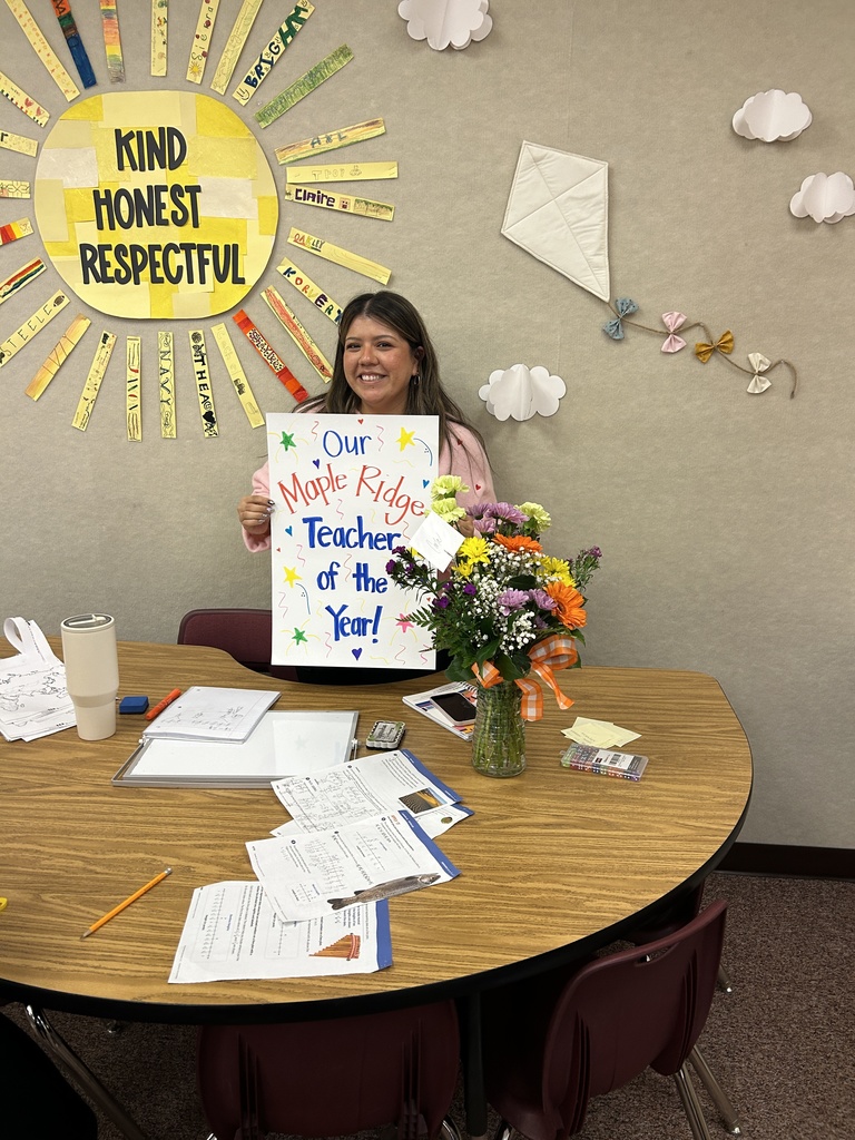 Carla Vela with flowers and Teacher of the Year poster.