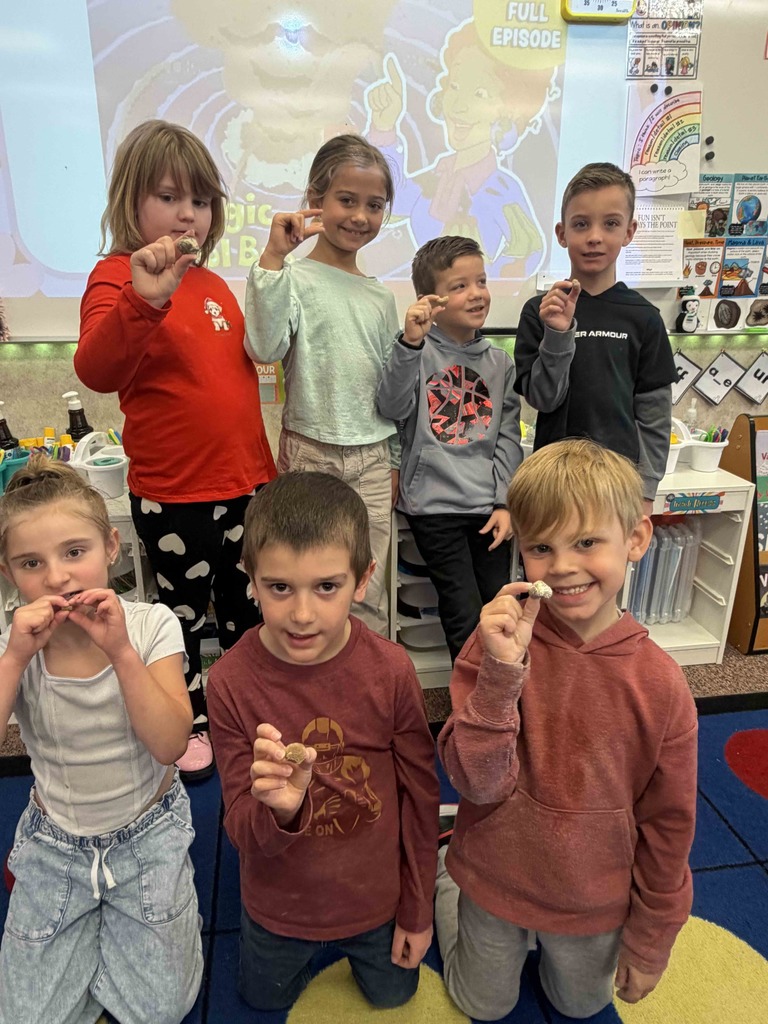 Students holding up different types of rocks.