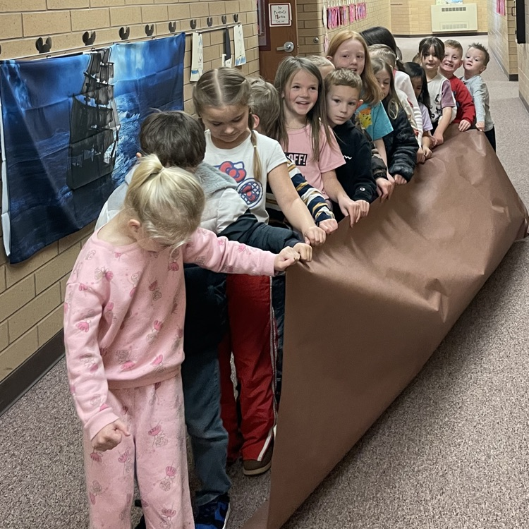 a group of kids holding to a long piece of paper to represent the mayflower 