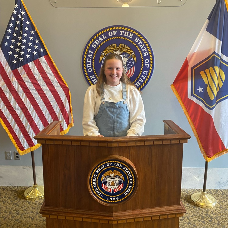 a student standing behind a podium with flags on either side 