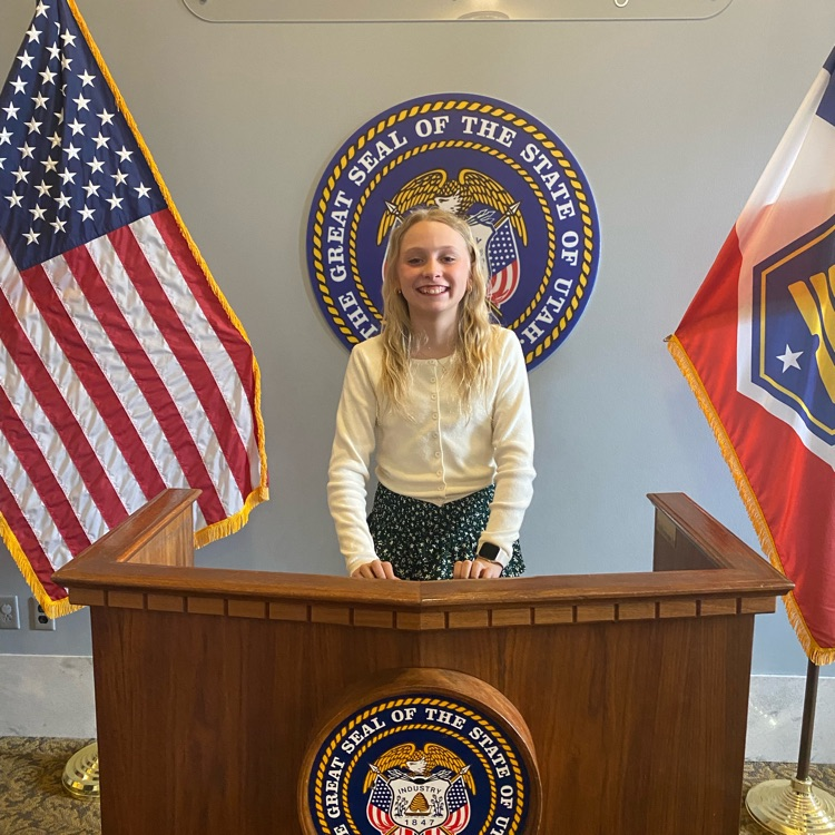 a student standing behind a podium with flags on either side 