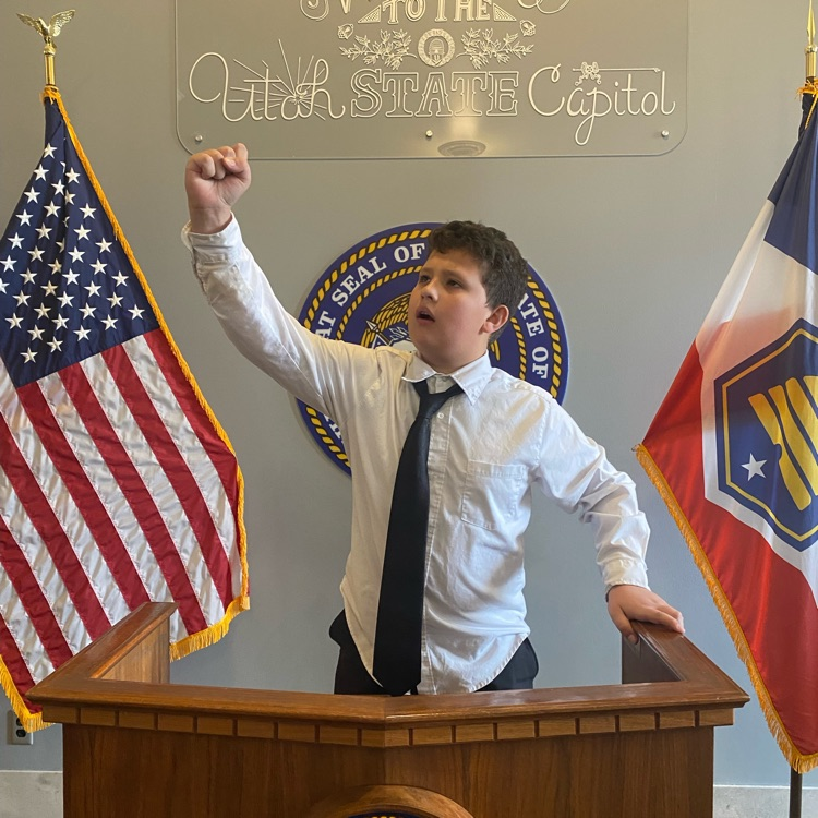 a student standing behind a podium with flags on either side 