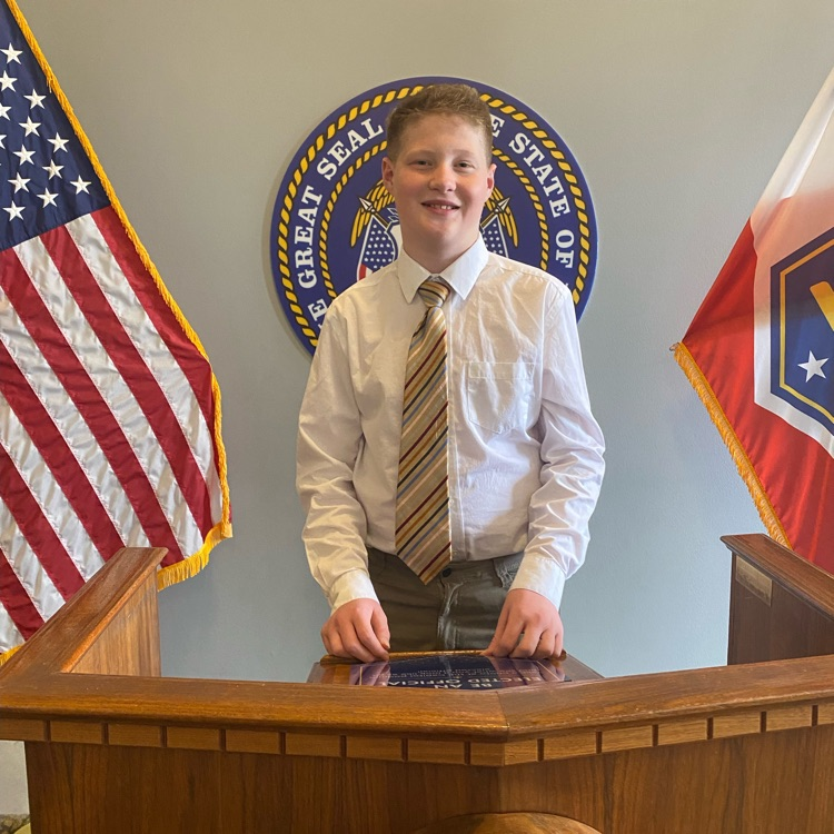 a student standing behind a podium with flags on either side 