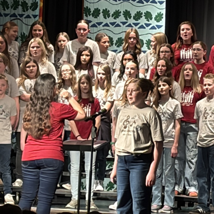 picture of soloist with choir behind her and the director’s back