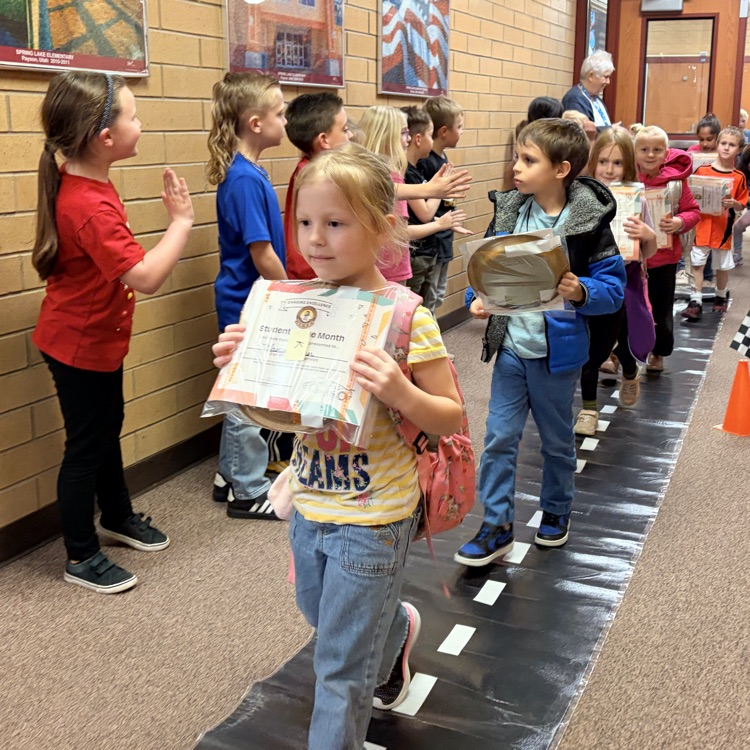 students of the month in a line while other kids cheer them on
